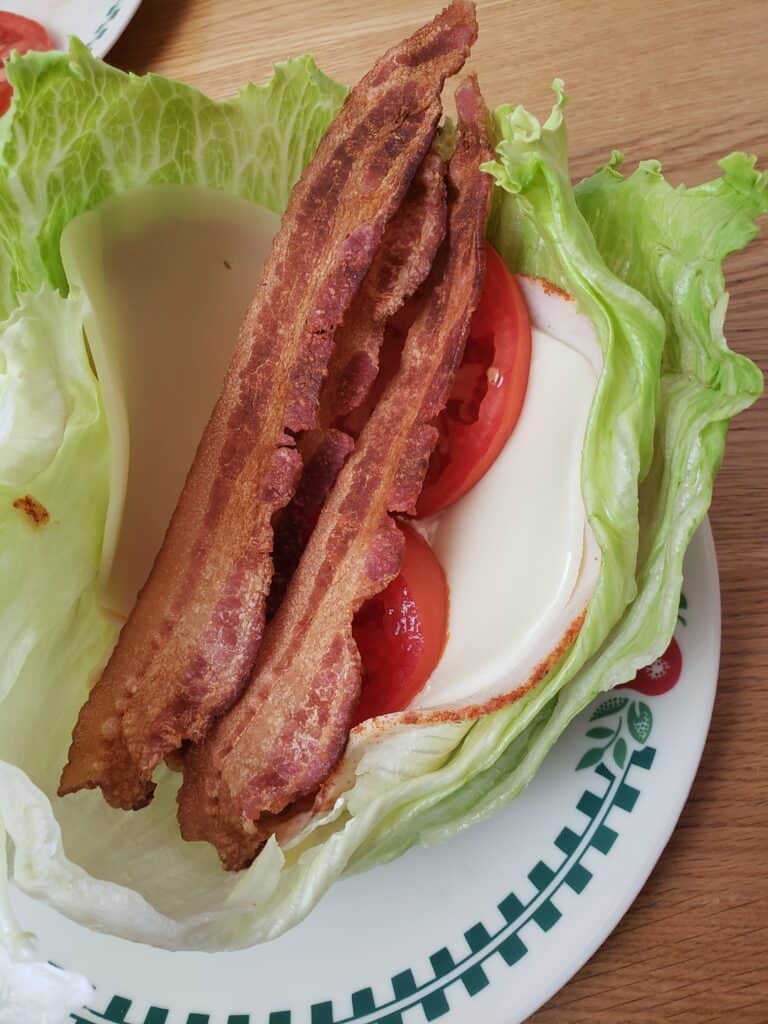 bacon and tomato on top of lunchmeat and cheese in lettuce leaves